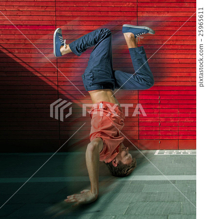 Break dancer doing handstand against colorful wall 25965611
