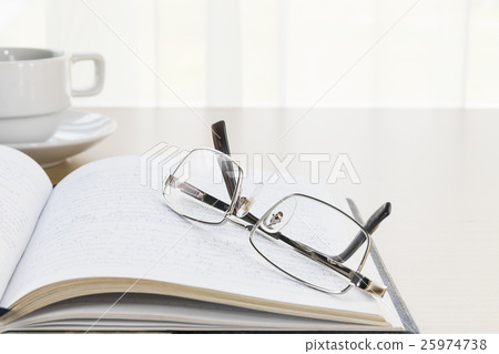 Eyeglasses put on a book with on the desk Eyeglasses put on a book with on the desk 25974738