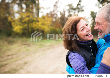 Beautiful senior couple running outside in sunny 25980291