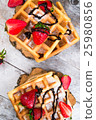 Belgium waffles with strawberries and chocolate.  25980856