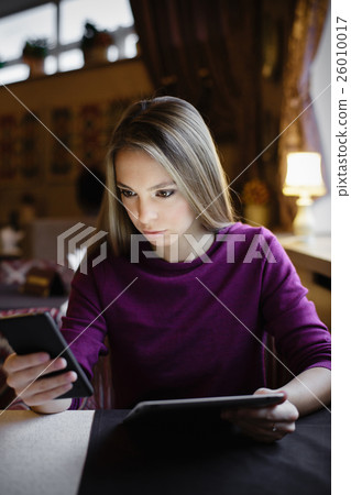 Thoughtful woman looking at smartphone Thoughtful woman looking at smartphone 26010017