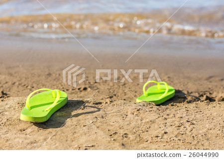 Dark green flip flops lie on the bank of the river Dark green flip flops lie on the bank of the river 26044990