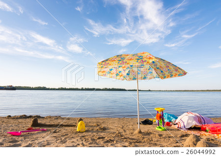 Parasol on the river bank, under which the scattered items and toys 26044992