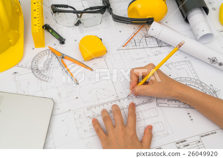 Hand over Construction plans with yellow helmet and drawing tools on blueprints . Hand over Construction plans with yellow helmet and drawing tools on blueprints . 26049920