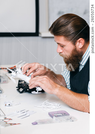 Bearded man examing new quadrocopter Bearded man examing new quadrocopter 26050734