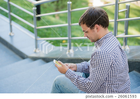Man uses his Mobile smart Phone outdoor while Man uses his Mobile smart Phone outdoor while 26061593