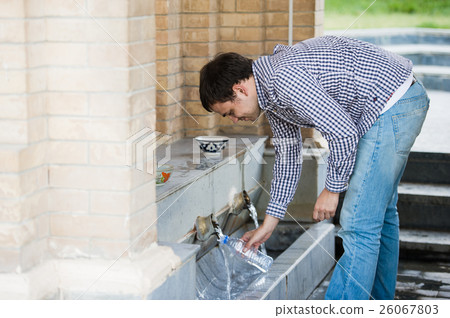 Man fills a bottle of mineral water from spring 26067803