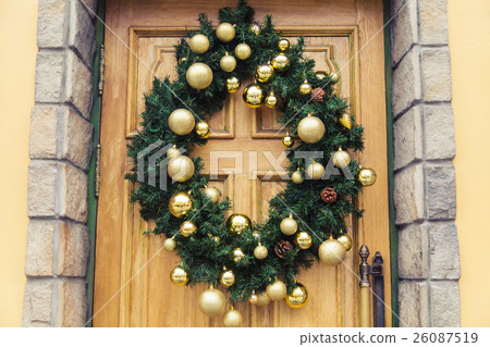 Christmas wreath with baubles and cones on a door. Christmas wreath with baubles and cones on a door. 26087519
