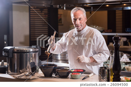 Smiling chef holding the ladle with a sauce Smiling chef holding the ladle with a sauce 26094500