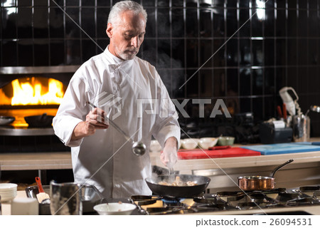 Involved chef mixing mushrooms on the frying pan 26094531