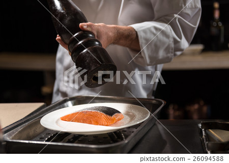 Concentrated chef putting salt on the salmon steak Concentrated chef putting salt on the salmon steak 26094588
