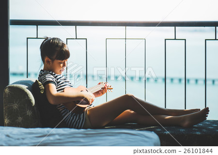 Asian girl playing ukulele near the window 26101844