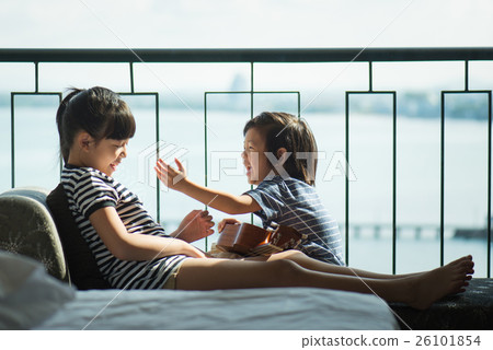 Asian girl playing ukulele near the window 26101854