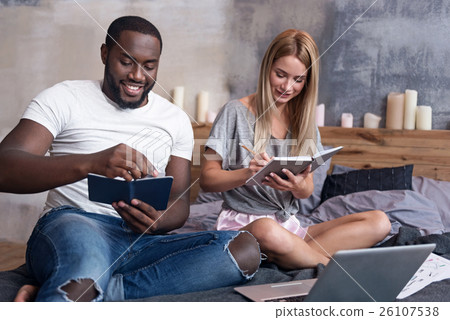 Young couple holding notebooks in bed 26107538