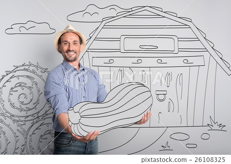 Handsome glad farmer holding pumpkin. Handsome glad farmer holding pumpkin. 26108325