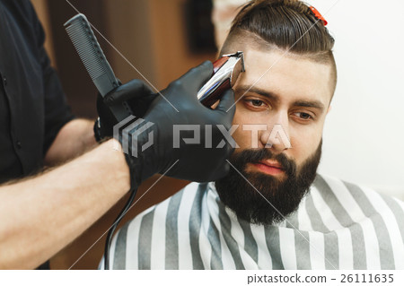 Man with dark hair doing a haircut 26111635