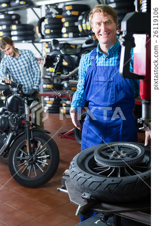 smiling technician man working with wheel for motorcycle smiling technician man working with wheel for motorcycle 26119106