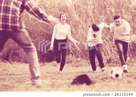 girl and three boys playing football in spring park and smiling 26119144