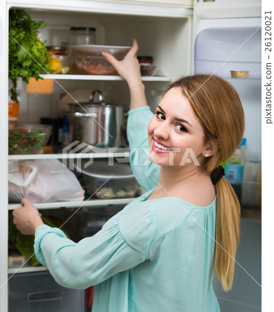 long-haired woman arranging space in fridge at home long-haired woman arranging space in fridge at home 26120021