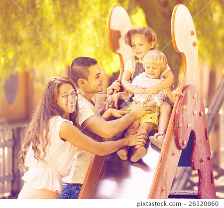 Smiling parents helping kids on slide 26120060