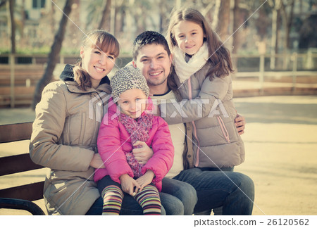 Parents with little daughters on bench. 26120562