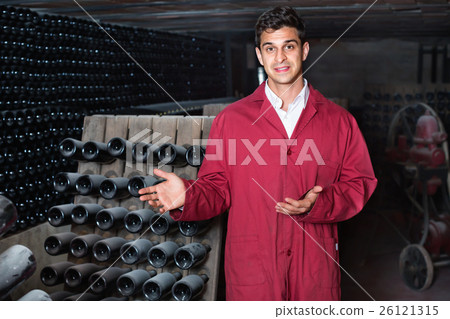 Man winery working in aging section with bottle racks in cellar 26121315