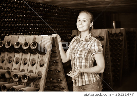 Woman winery employee standing in aging section with bottles Woman winery employee standing in aging section with bottles 26121477