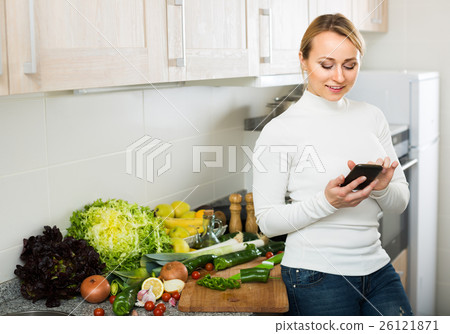 Housewife with phone at home kitchen. Housewife with phone at home kitchen. 26121871