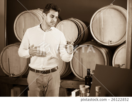 man with glass of brandy in winery store . man with glass of brandy in winery store . 26122852