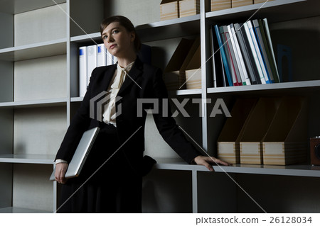 Business woman nestling in front of a bookshelf Business woman nestling in front of a bookshelf 26128034