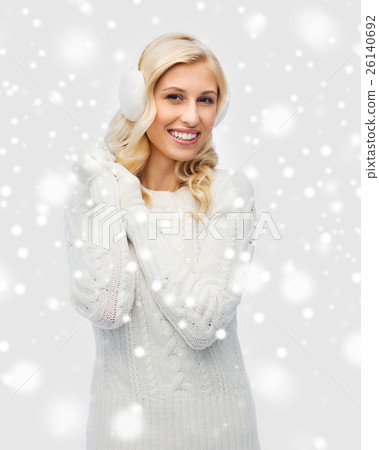 smiling young woman in winter earmuffs and sweater smiling young woman in winter earmuffs and sweater 26140692