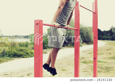 young man exercising on horizontal bar outdoors 26141180