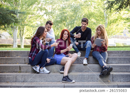 Young people using smartphone and tablet computers outdoors 26155083