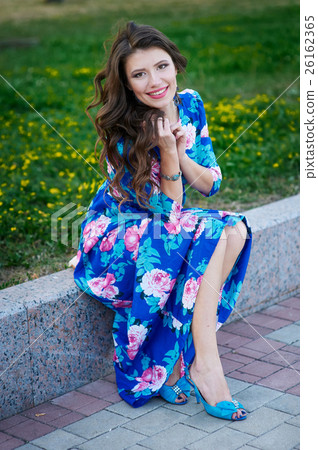 beautiful smiling woman in a blue dress sitting on 26162365