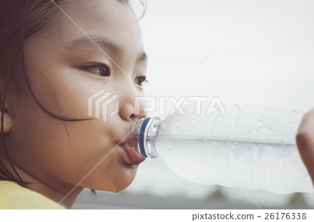 Cute girl is drinking water from plastic bottle.  26176338