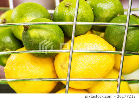 Lemons and green limes in the metal basket Lemons and green limes in the metal basket 26177212