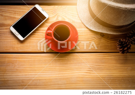 Coffee cup on wooden plank with cell phone and hat Coffee cup on wooden plank with cell phone and hat 26182275