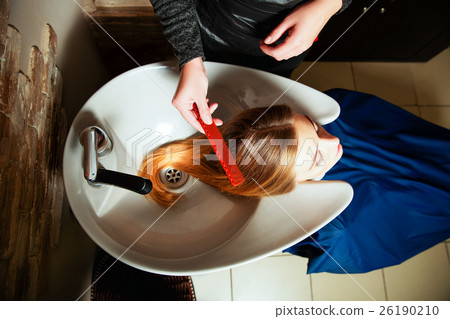 Hairdresser washing young woman's hair in salon. 26190210