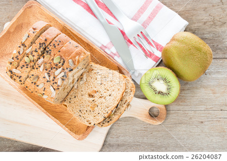 Whole wheat bread and kiwi fruit on table. 26204087