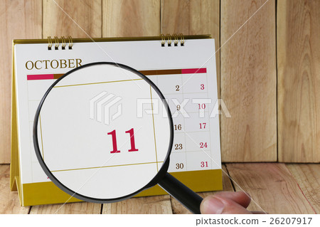 Magnifying glass in hand on calendar you can look Eleventh date of month,Focus number eleven in October. Magnifying glass in hand on calendar you can look Eleventh date of month,Focus number eleven in October. 26207917