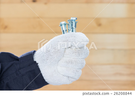 Hand in glove holding metal anchor bolts Hand in glove holding metal anchor bolts 26208844