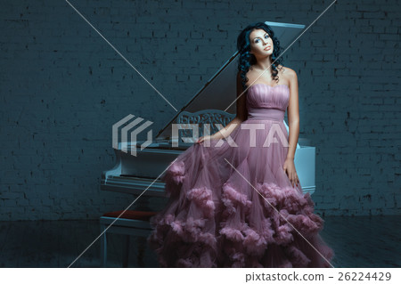 Beautiful woman posing next to a white piano. Beautiful woman posing next to a white piano. 26224429