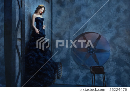 Woman in a long black dress standing dark room. Woman in a long black dress standing dark room. 26224476