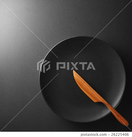 Black plate with knife on a background. 26225406