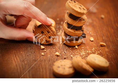 Female hand holds small bisqiut with cookies and chocolate piece 26225656