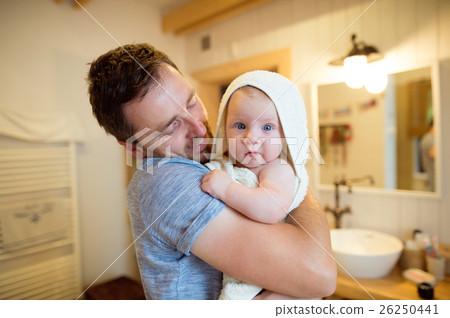 Young father holding his son wrapped in towel Young father holding his son wrapped in towel 26250441