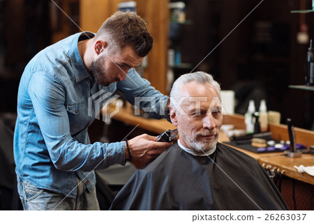 Handsome barber trimming hair of old man Handsome barber trimming hair of old man 26263037