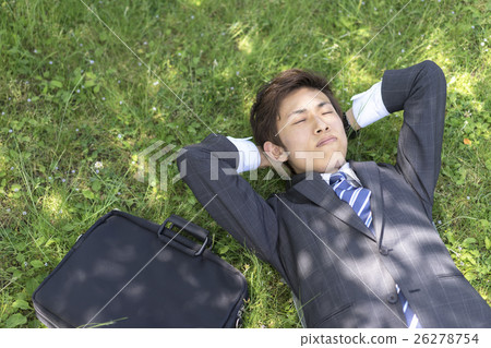 A businessman lying down on the grass 26278754