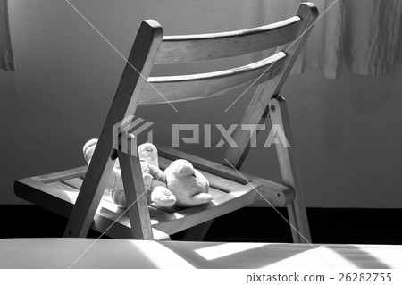 Cute teddy bear lying alone on chair near window Cute teddy bear lying alone on chair near window 26282755