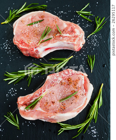 Raw pork steaks with rosemary on black stone Raw pork steaks with rosemary on black stone 26295117